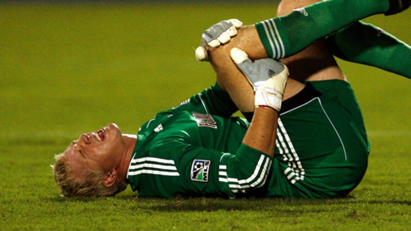 Dallas goalie Kevin Hartman clutches his knee after his incident with NY's Thierry Henry.